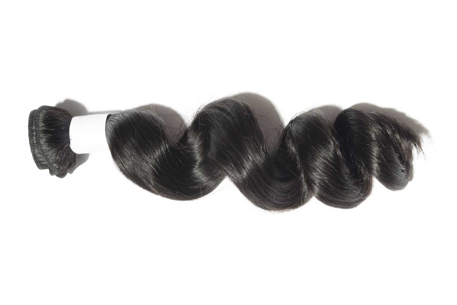A coiled bundle of shiny, black hair extensions against a white background.
