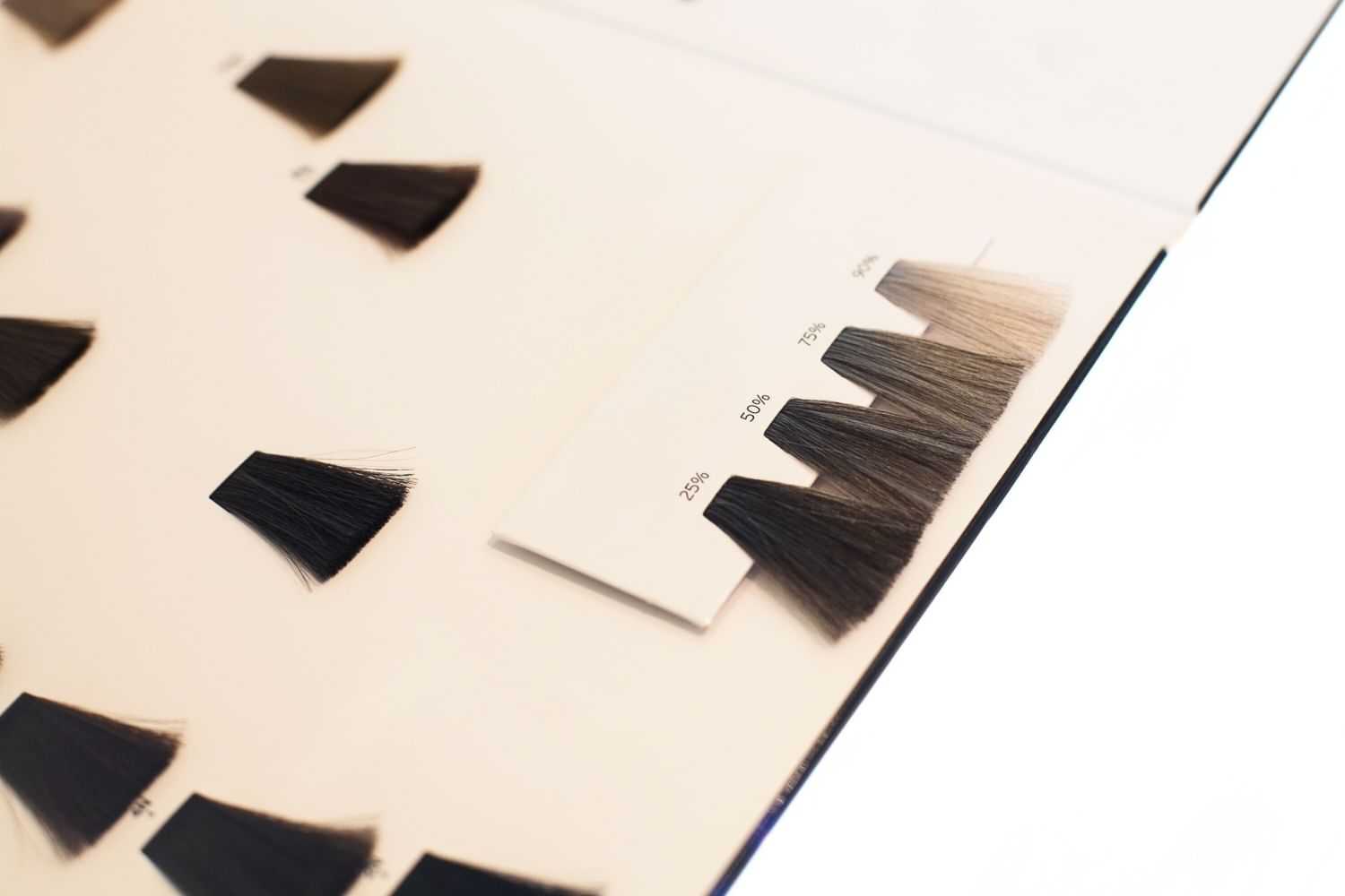 Various hair color samples displayed on a board, ranging from black to light blonde shades.